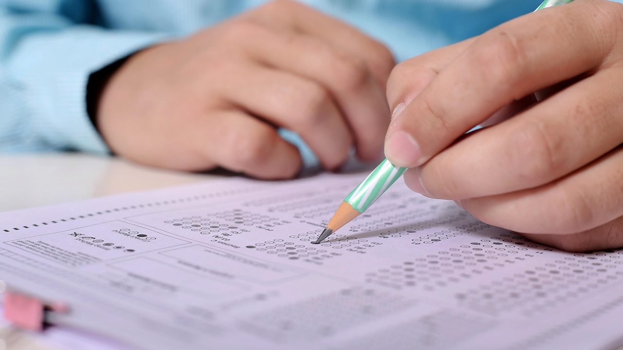 Rows of empty student desks arranged in a formal examination room.