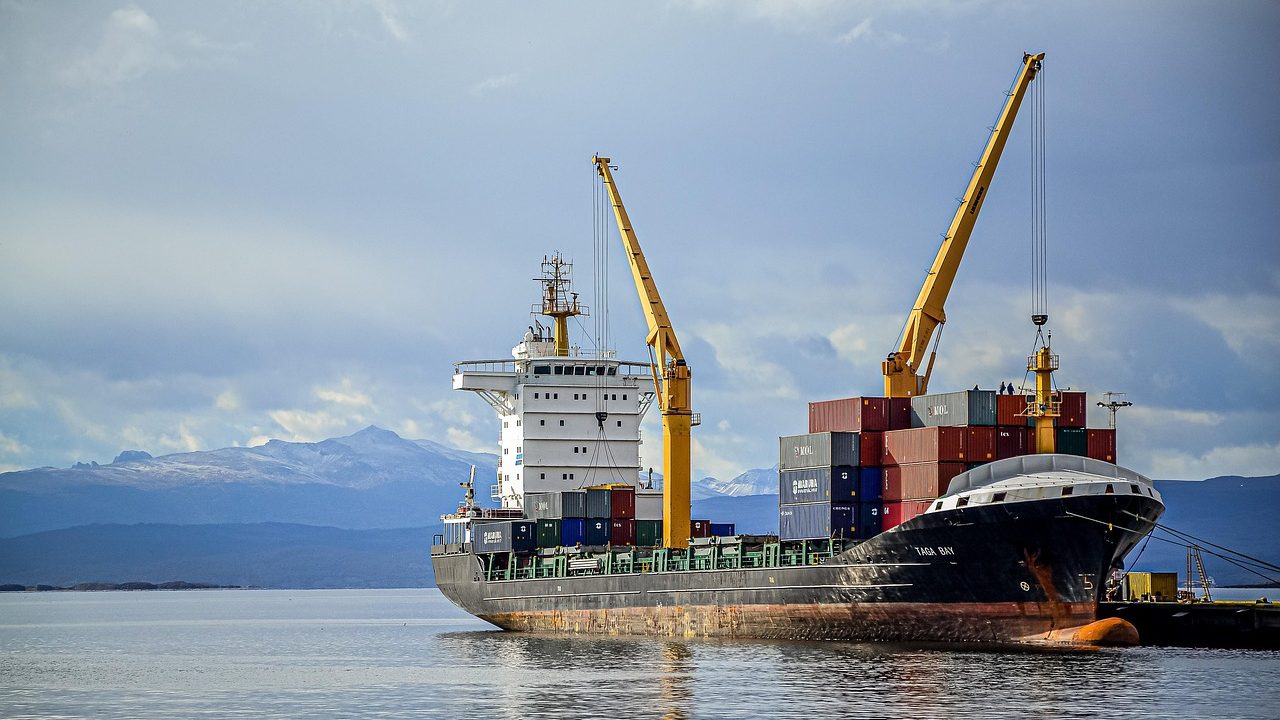 A large cargo vessel passing through a narrow strait with rocky coastline visible.