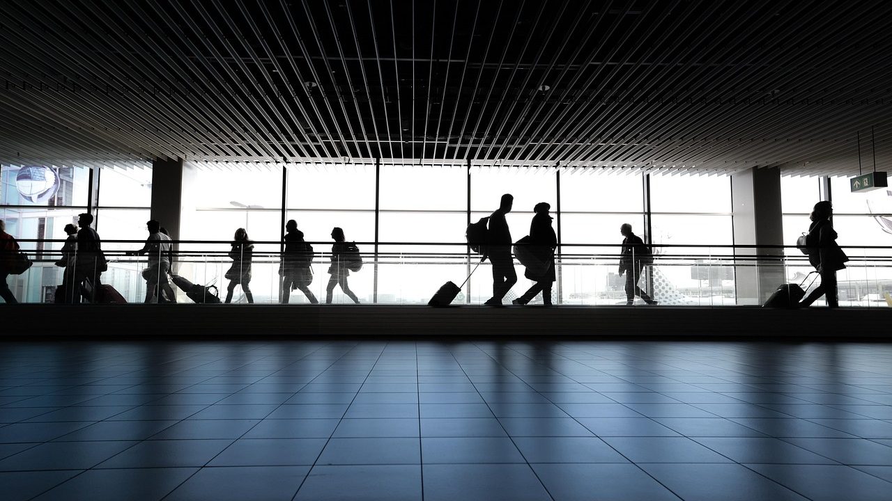 A bright airport departure gate terminal with large windows overlooking the tarmac.