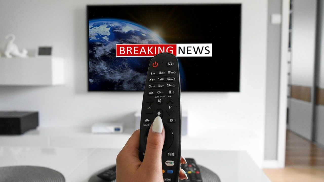 Multiple television screens in a broadcast studio displaying world news feeds.
