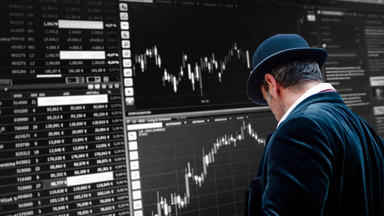Traders stand at workstations on a busy stock exchange trading floor.