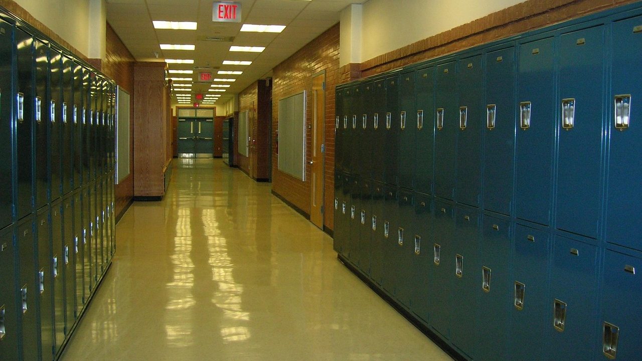 An empty school hallway lined with blue metal lockers before the start of the school day.