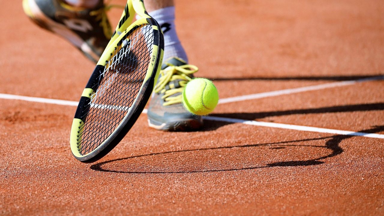Young players competing on an outdoor hard-court tennis court during a tournament.