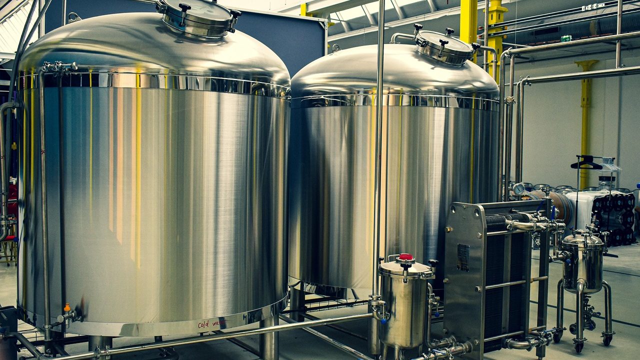 Large stainless steel fermentation tanks inside an industrial brewery facility.