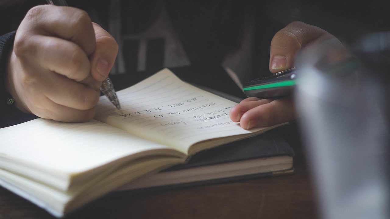 High school students working on laptops at desks in a bright classroom.
