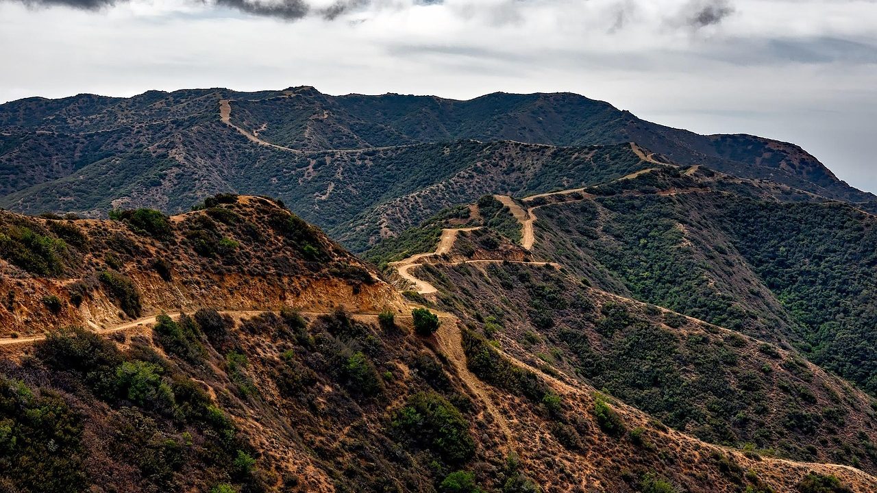 A winding dirt trail through dry Southern California chaparral on a clear fall afternoon.