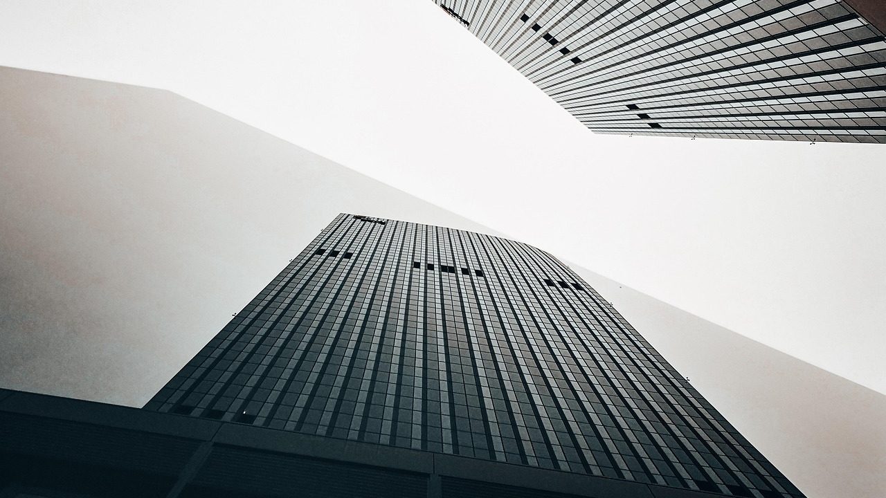 Modern glass-and-steel residential tower rising above a city street on a clear afternoon.