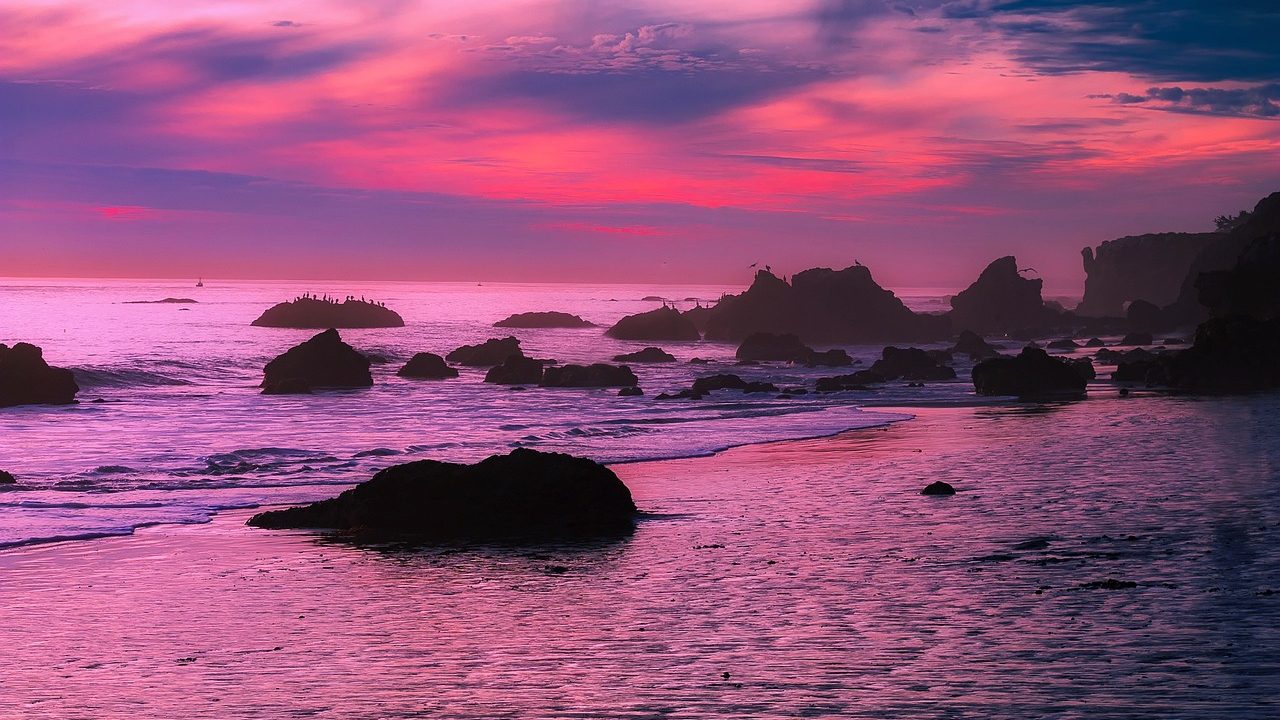 Warm light at sunset over a rocky Southern California coastline with calm surf.