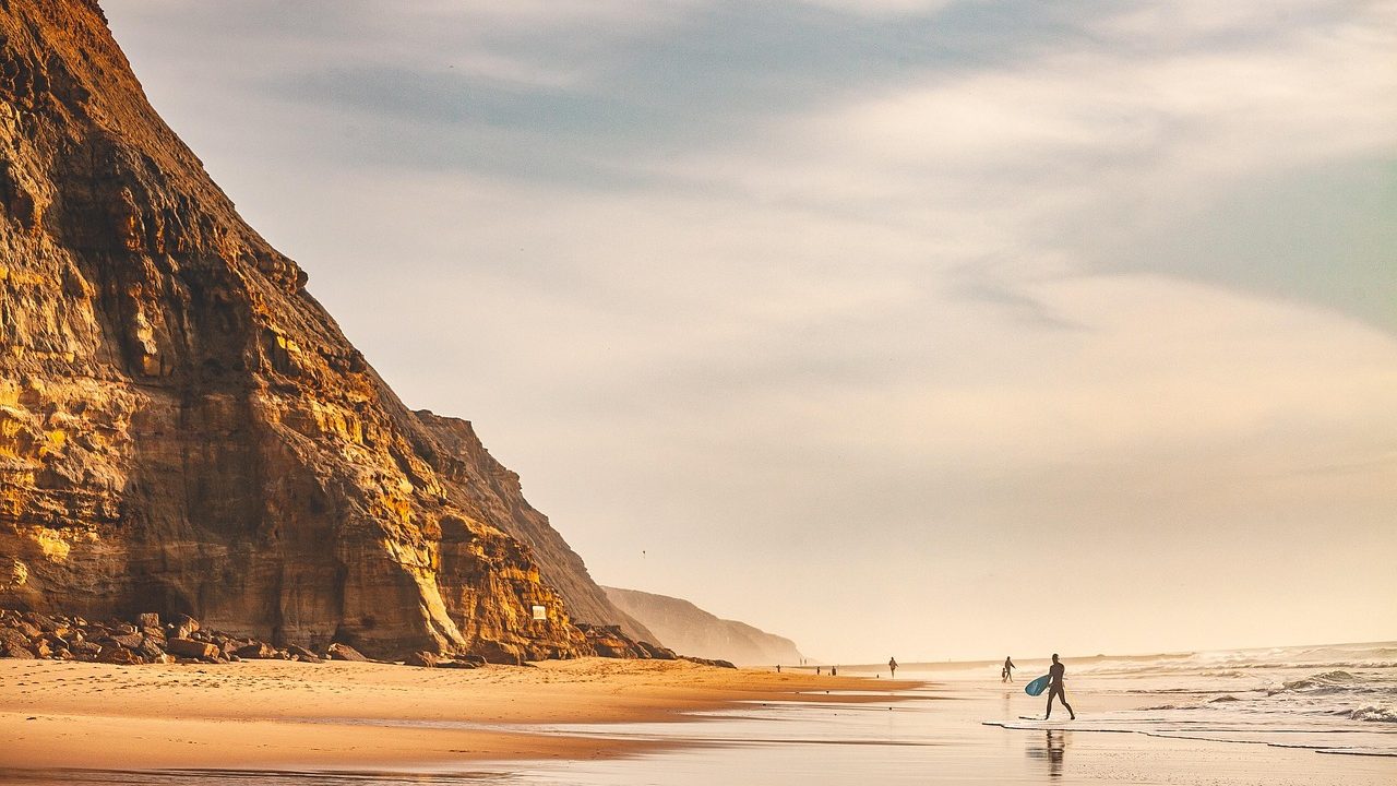 A weathered coastal bluff edge overlooking the Pacific Ocean under overcast skies.
